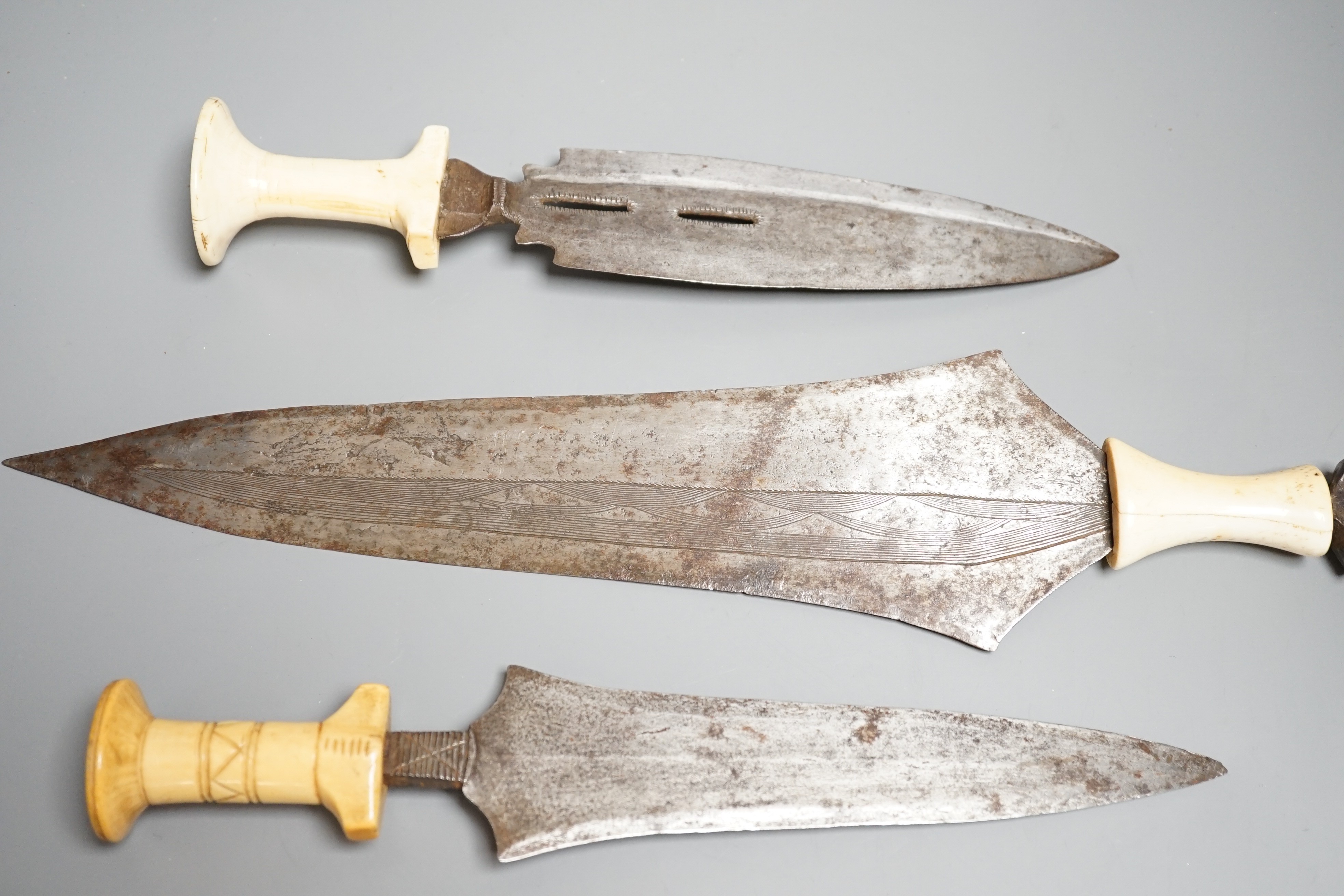 Three assorted African tribal daggers c.1900, each with ivory handle including two with decorated blades and one with iron pommel, maximum 40cms